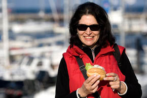 Eine Frau am Hafen genießt ein Fischbrötchen...